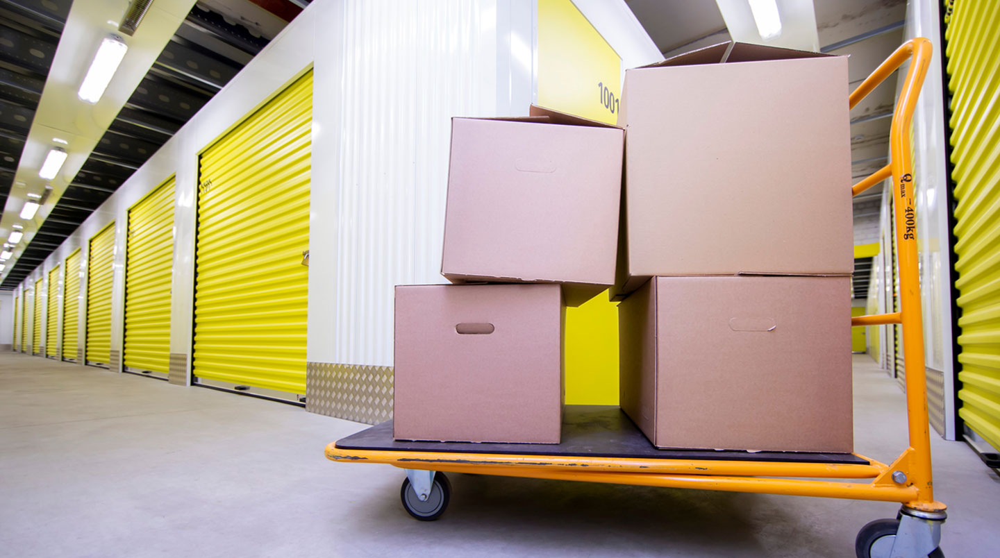 Professionnel chargeant du matériel dans un box de stockage en libre-service avec porte ouverte et étagères visibles